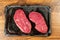 Two fresh uncooked fillet steaks on a black plastic tray