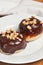 Two freshly baked, homemade yeast donuts with chocolate covering and peanuts on top