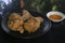 Two fried chicken breaded on a brown plate with sauce.