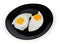Two fried eggs prepared sunny side up on black dish