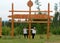 Two friends of an Asian Yakut stand under a wooden sign with the name of the village `Tenke` in Northern Russia in the taiga