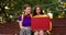 Two friends: a brunette girl in a yellow sweater and a girl with a short haircut in a purple top sit on brown stands and