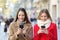 Two friends checking smart phones in the street