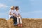 Two friends children are sitting on hay bales after harvest on blue sky background. Happy boys are basking in the sun on haystack