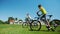 Two friends on cycle ride on green grass field together