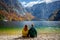Two friends enjoying scenic alpine lake view with majestic mountains in the background