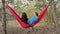Two friends laugh and talk while lying on a hammock of the forest The idea of a relaxing weekend getaway together