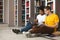 Two friends making homework on floor in campus library