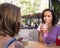 Two friends meeting together and drinking juice in urban background with buildings and trees during summer bright light. Concept