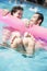 Two friends in a pool holding onto an inflatable raft with feet sticking out of the water