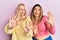 Two friends standing together over pink background afraid and terrified with fear expression stop gesture with hands, shouting in