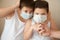 Two frightened boys in medical mask looking at hand with syringe