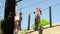 two frightened but brave girls in helmet, T-shirt and shorts climbs in rope park