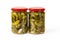 Two full glass jars of pickled gherkins isolated on a white background. Whole green cornichons marinated with dill, garlic and