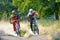 Two Fully Equipped Professional Downhill Cyclists Riding Bikes on the Summer Trail