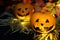 Two funny or angry pumpkins Jack Lantern head in the hay, against the background of autumn yellow leaves. One face after another.