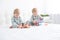 Two funny boys brothers twins on white bed in pajamas playing in magnetic constructor