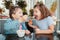 Two funny Caucasian little preschool sisters siblings eat dessert play in cafe.