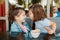 Two funny Caucasian little preschool sisters siblings kiss in a cafe. Friends girls having fun together. Kids eat have breakfast