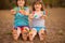 Two funny child girls sitting on grass and waving painted hands and foot in funny faces