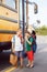 Two funny happy Caucasian boys students kids eating apples near yellow bus on 1 September day.