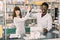 Two funny happy colleages pharmacists, African man and Caucasian woman working in drugstore, smiling. giving five and