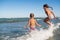 Two funny little girls jump in the noisy sea waves
