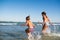 Two funny little girls jump in the noisy sea waves