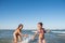 Two funny little girls jump in the noisy sea waves