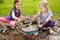 Two funny little girls playing in a large wet mud puddle on sunny summer day. Children getting dirty while digging in muddy soil