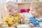 Two funny smiling very positive kids eating in kindergarten