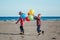 Two funny white Caucasian children kids with colorful bunch of balloons, playing running on beach on sunset, autumn summer