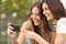 Two funny women friends laughing and sharing media in a smart phone