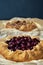 Two galettes with ripe red cherry and walnuts on dark background. Homemade sweet open pie