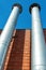 Two galvanized chimneys on the facade of a red brick building, vertical photo