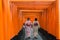 Two geishas among red wooden Tori Gate at Fushimi Inari Shrine i