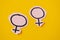 Two gender symbols Venus cut from pink paper on yellow background. Concept lgbt