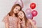 Two gentle beautiful girls teen sisters cuddle in a room with balloons