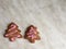 two ginger herringbone-shaped cookies, with pink icing sugar, grey background