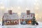 Two gingerbread houses, tree and people sitting on a bench, winter scene