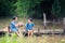 Two girl children sitting and playing water together on wooden bridge over swamp, Asian kids playing water