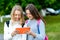 Two girl friends schoolgirl. Summer in nature. In her hands holds a tablet. Behind the backpack. The concept of watching