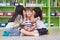 Two girl kids whisper secret at ear of boy in library at kindergarten preschool,Fun and happy children,back to school concept