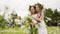 Two girl teenager in floral wreath with flowers bouquet standing on blooming field. Romantic girls with flower bouquet