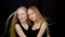 Two girl teenager posing on black background in studio and hair moving on wind