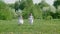 Two girl teenager in white dress running on green lawn in flowering garden. Running girl friends on summer meadow on
