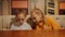 Two girl teenagers looking something under table in home. Girl friends looking gadget under table on kitchen.