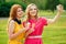 Two girlfriends beautiful young ginger redhead woman in a yellow dress and blonde female person in a pink dress eating