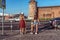 Two girlfriends girl, against background of road transition, stand with skateboards, longboard, view from the rear, in