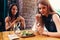 Two girlfriends having healthy lunch in cafe. Young woman taking picture of food with smartphone posting on social media